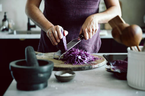 Rotkohl wird mit einer Küchenreibe geraspelt.