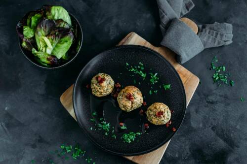Selbst gemachte Sauerkraut-Knödel auf schwarzem Teller.