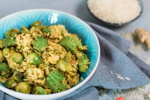 Schnelle asiatische Reispfanne in blauer Schüssel vor hellem Hintergrund.