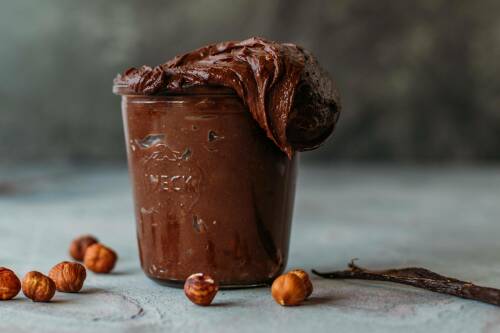 Schoko Nuss Aufstrich vegan im Glas vor dunklem Hintergrund.