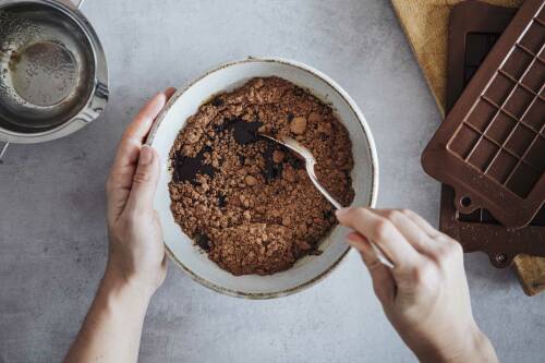 Geschmolzene Kakaobutter mit Kakao in Schüssel vermengt vor hellem Hintergrund.