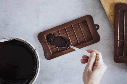 Selbstgemachte Schokolade mit Löffel in Form gegossen vor hellem Hintergrund.