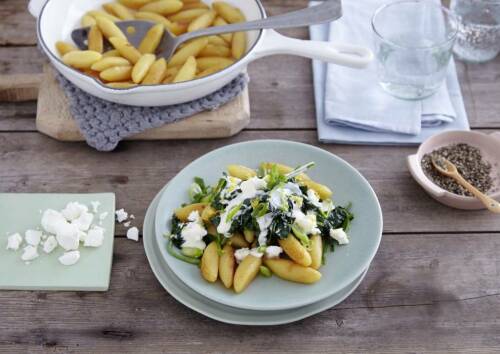 Schupfnudeln mit Spinat und Feta auf einem Teller, daneben die Schupfnudelnpfanne, von oben fotografiert
