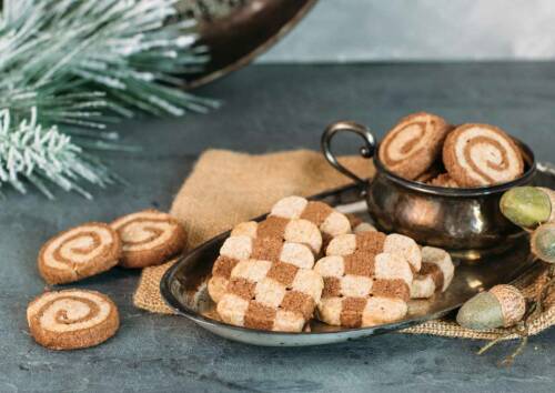 Plätzchen mit hellem und dunklem Teig auf einer Platte angerichtet. Von der Seite fotografiert.
