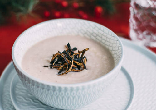Weiß-rosa Suppe aus Schwarzwurzel mit knusprigen Gemüsechips. Von oben fotografiert.