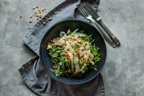 Schwarzwurzelsalat mit Vanilledressing in schwarzer Schüssel vor dunklem Hintergrund.