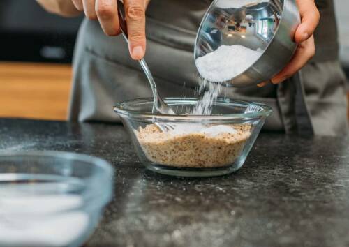 Selbst gemachter Puderzucker aus Xylit wird in eine Schüssel mit gemahlenen Mandeln gegeben.