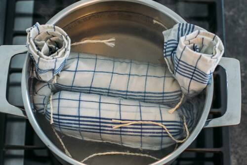 Topf mit Serviettenknödel darin. Wenn die Knödel an die Oberfläche steigen und sich zu drehen beginnen, sollten sie herausgenommen werden. Zu sehen ist die Draufsicht auf einen Topf.