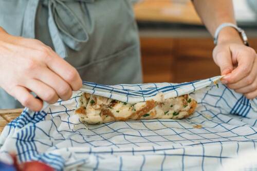 Die Semmelknödel-Masse wird in ein Geschirrtuch gerollt und darin abgebrüht, sogenannte Serviettenknödel.