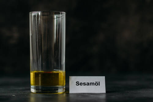 Sesamöl in Glas vor dunklem Hintergrund.