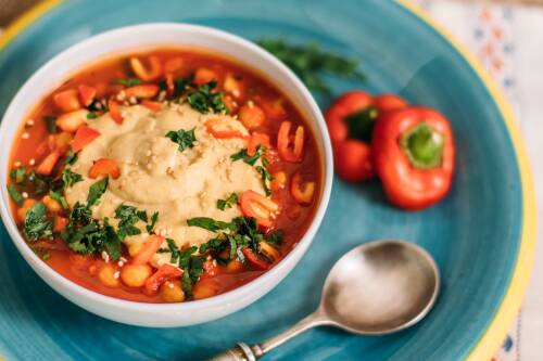 Israelisches Gericht mit Hummus und Tomaten-Paprika-Sauce in einer Schüssel, von oben fotografiert.
