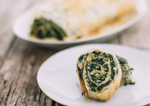 Nussiger Strudel mit Spinatfüllung als Scheibe auf einem Teller. Von vorne fotografiert.