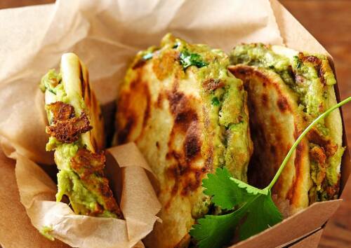 In diesem Gericht lässt sich Spinat super in die mexikanische Küche integrieren, die klassischen Quesadillas kommen dadurch in einer neuen Variante daher. Zu sehen sind drei Spinat-Quesadillas in Backpapier, von oben fotografiert.