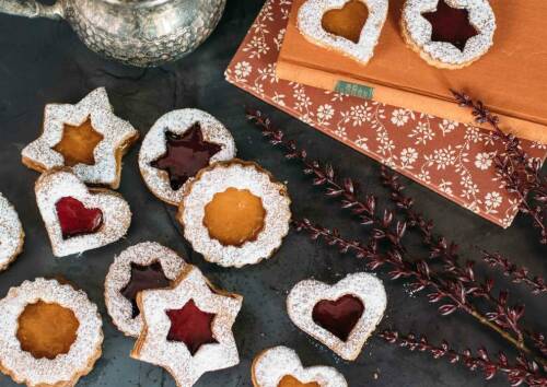 Schöne bunte Spitzbuben mit dreierlei Marmelade gefüllt. Sterne, Kreise und Herzen mit Puderzucker bestäubt. Von oben fotografiert.