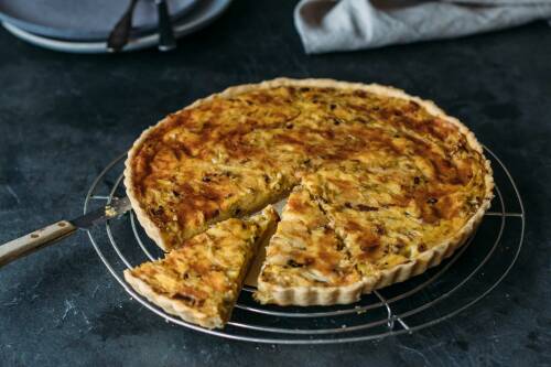 Spitzkohlquiche angeschnitten auf Blech vor dunklem Hintergrund.