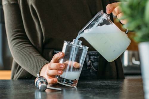 Ausgekühltes Spülmittel wird in einen Seifenspender aus Glas gefüllt.