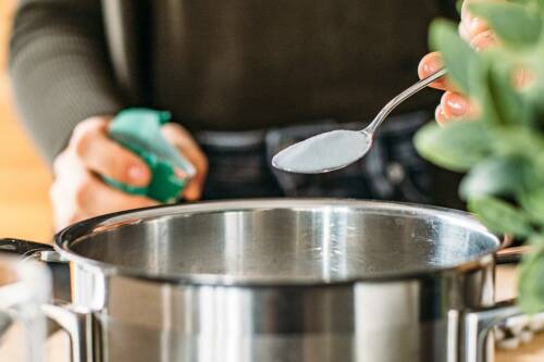 Natron auf einem Löffel, das in einen  Topf gegeben wird.