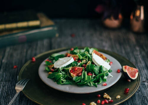 Herbstlicher Salat mit Feigen, Granatapfel und Ziegenkäse von der Seite fotografiert.