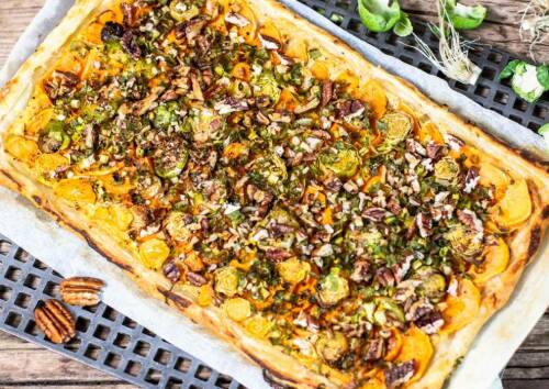 Blech mit einer Tarte aus Blätterteig, Süßkartoffel, Rosenkohl und Nüssen. Von oben fotografiert.
