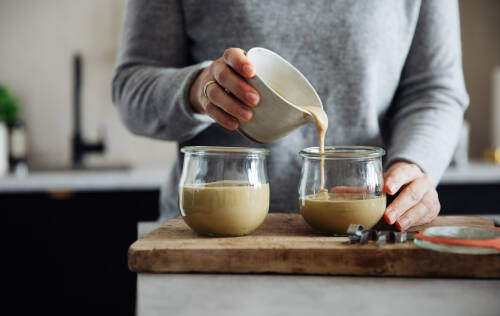 Tahin in Weckgläsern mit Händen vor hellem Hintergrund.