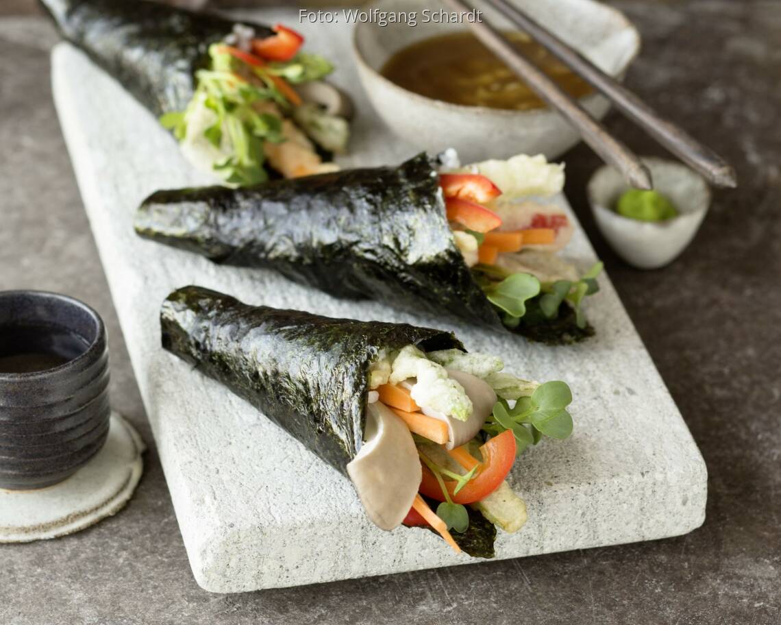 Drei Tempura Temaki hintereinander auf einem hellen Brett angeordnet