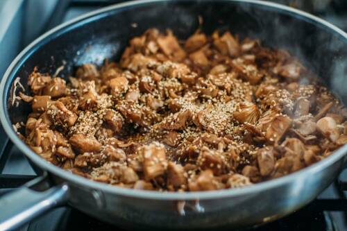 Tofu marinieren in Pfanne vor dunklem Hintergrund.