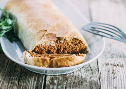 Rolle Tofubraten, angeschnitten auf einem Teller. Von vorne fotografiert.