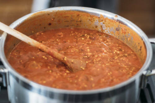 Vegane Bolognese in Topf mit Kochlöffel.