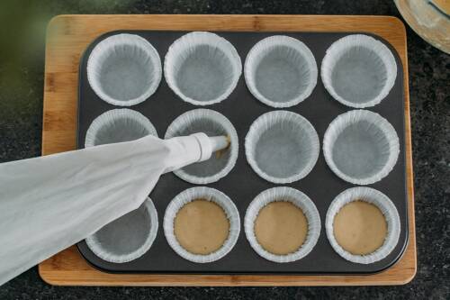 vegane Cupcakes  mit Spritzbeutel in Muffinblech.