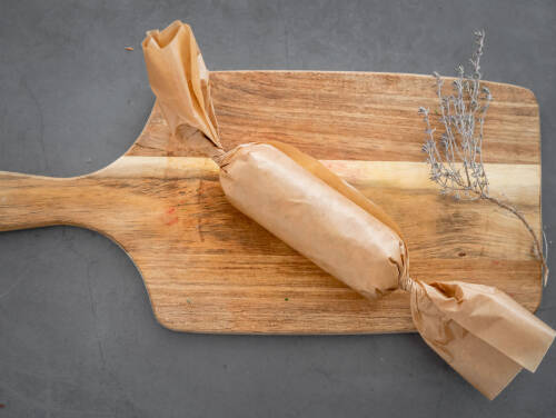 vegane Kräuterbutter in Backpapier zu einer Rolle geformt