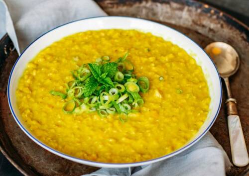 Suppenteller mit gelber Linsensuppe garniert mit Lauchzwiebeln