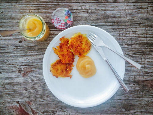 Vegane Reiberdatschi mit Apfelmus auf Teller vor dunklem Hintergrund.