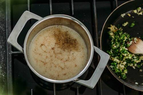 Mandeldrink und Muskat in Topf neben Pfanne vor dunklem Hintergrund.