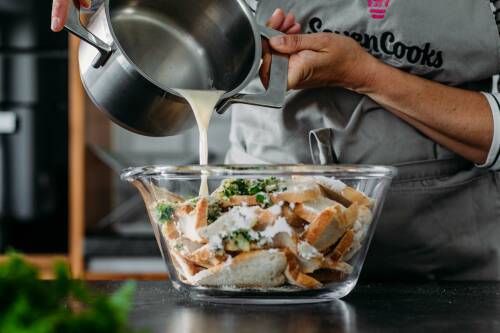 Semmeln und Petersilie in Schüssel mit Topf und Mandelmilch vor hellem Hintergrund.