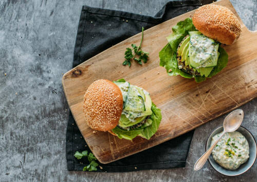 Frisch zubereiteter veganer Burger mit Mangold von oben fotografiert auf einem Holzbrett.