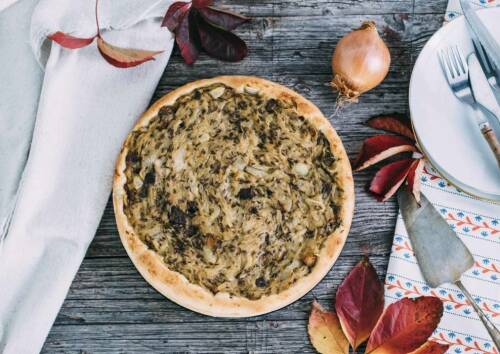Veganer Zwiebelkuchen mit herbstlicher Dekoration daneben, von oben fotografiert.