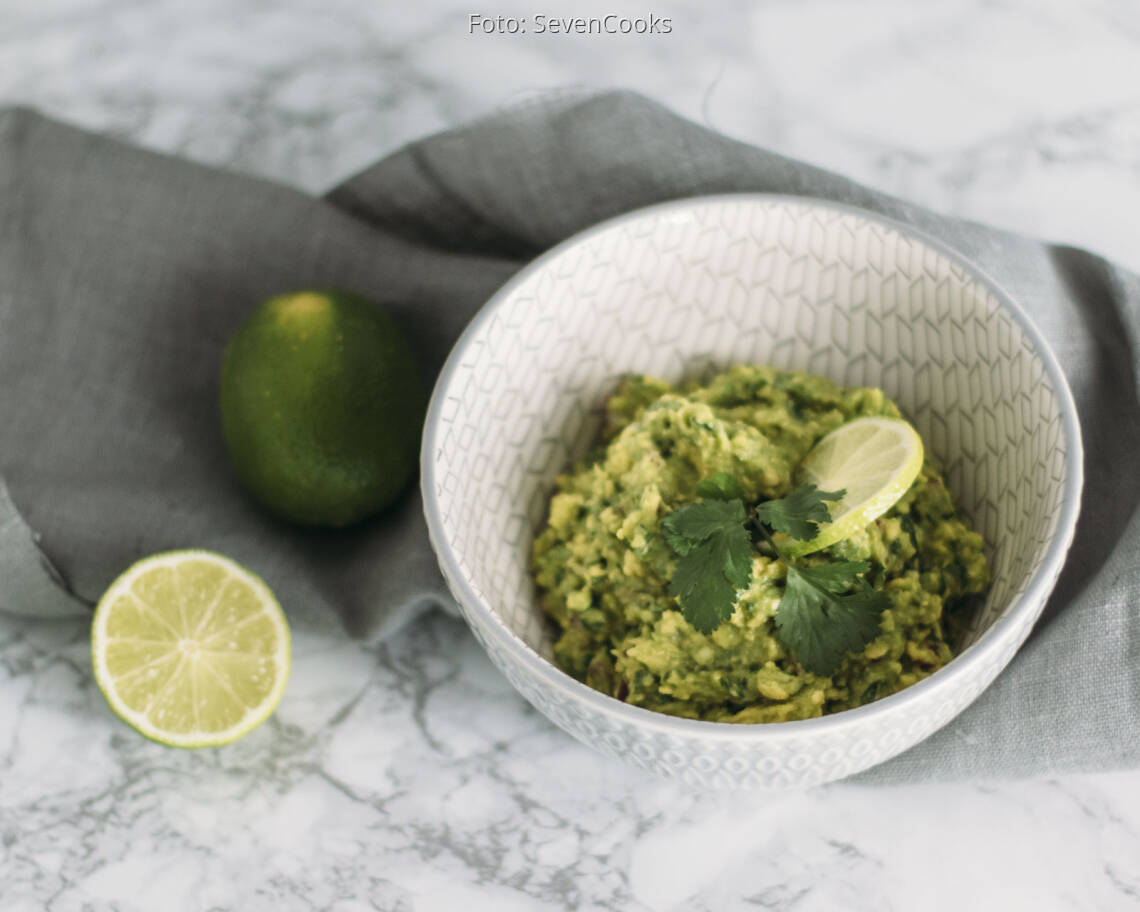 Veganes Rezept: Guacamole mit aufgeschnittener Limette in Schüssel angerichtet