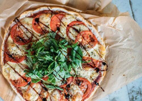 Fladenbrot Pizza belegt mit Tomaten Mozzarella und Rucola.