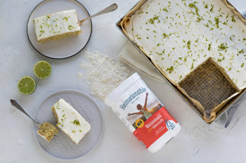 Selbst gemachter Zucchini-Blechkuchen, ein Stück auf einem Teller, der Rest auf einem Blech