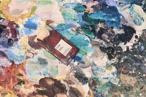 Eine Tafel VIVANI Schokolade Praliné Vollmilch auf künstlerischem Hintergrund mit Farbflecken.