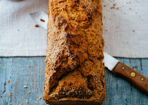 Vollkornbrot mit Messer vor hellem Hintergrund.