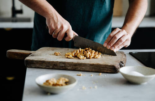 Walnüsse werden auf einem braunen Holzbrett gehackt.
