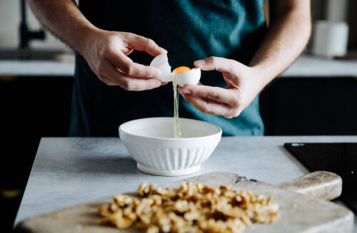 Ein Ei wird über einer weißen Schüssel getrennt.