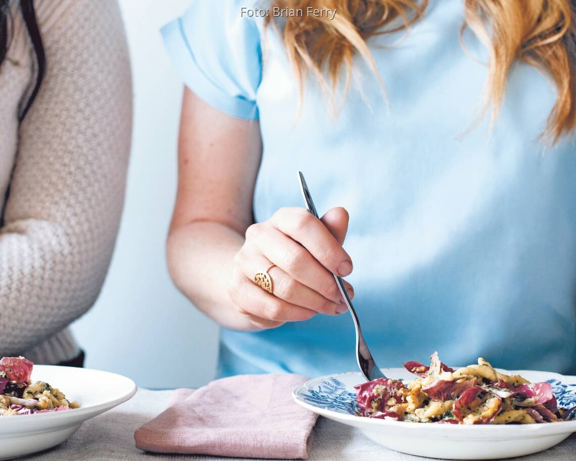 Nudeln mit Walnuss-Majoran Pesto. Eine Frau sticht mit der Gabel in die Nudeln auf dem Teller