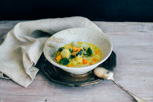 Wintergemüseeintopf in weißer Schüssel vor hellem Hintergrund.