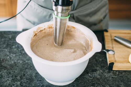 Zimteis in Rührschüssel mit Pürierstab vor hellem Hintergrund.