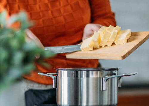 Klein geschnittene Butter auf einem Brett, welche im Topf geschmolzen wird