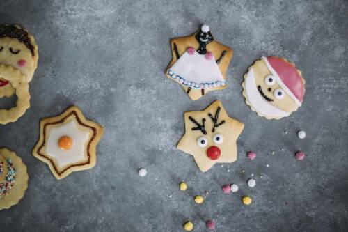 Butterplätzchen mit buntem Zuckerguss und Perlen dekoriert: Stern, Nikolaus, Engel. Von oben fotografiert.