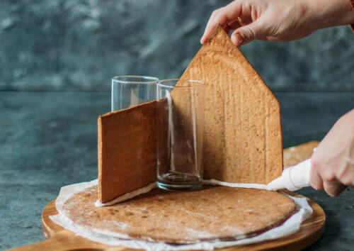 Seitenteile des Lebkuchenhauses werden mit Zuckerguss zusammengeklebt